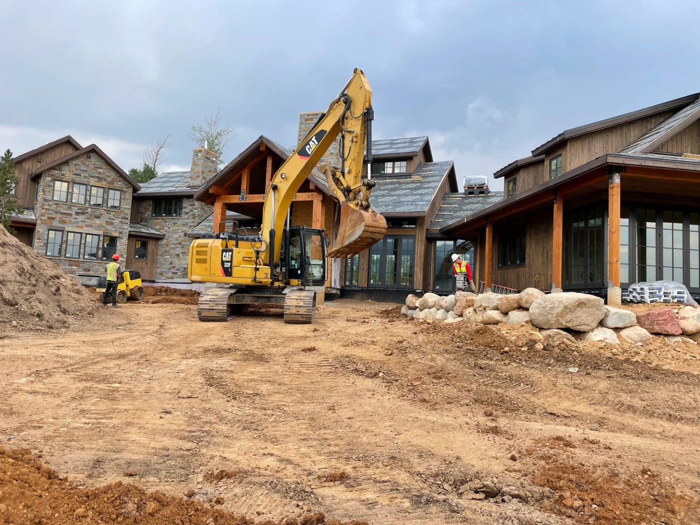 CAT excavator and crew performing site work at a mountain residential construction site in Colorado